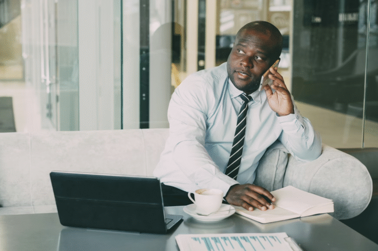 african americn sitting on a white couch talking on a cellphone